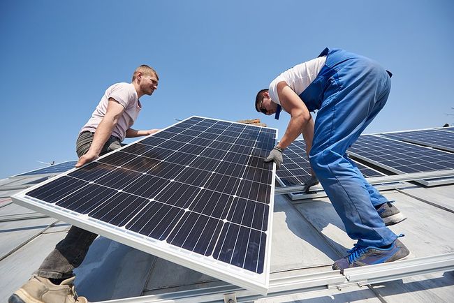 two people installing a solar panel